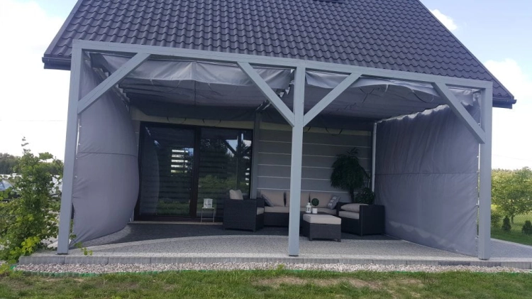 Custom waterproof grey garden curtains installed on a modern wooden pergola with outdoor lounge furniture.