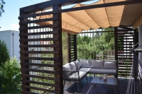 Custom waterproof premium roman blind installed on a dark wood pergola with outdoor sofa and coffee table