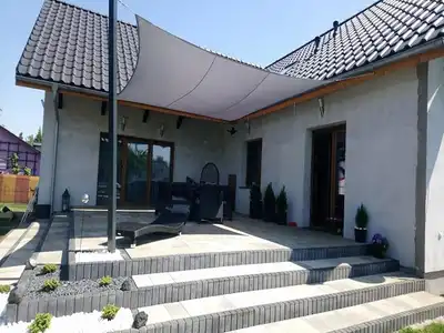 Wodoszczelny-zagiel-ogrodowy-premium-3x4m-zamontowany-nad-nowoczesnym-tarasem-przy-domu-jednorodzinnym